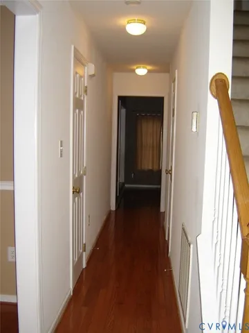 a view of a hallway with wooden floor and stairs
