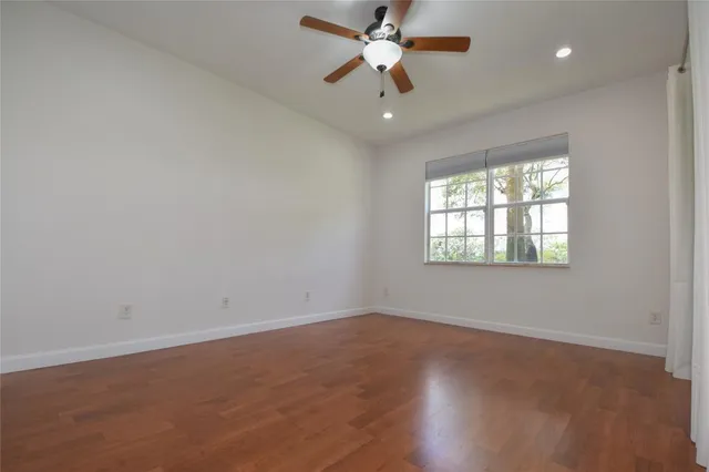 an empty room with wooden floor fan and windows