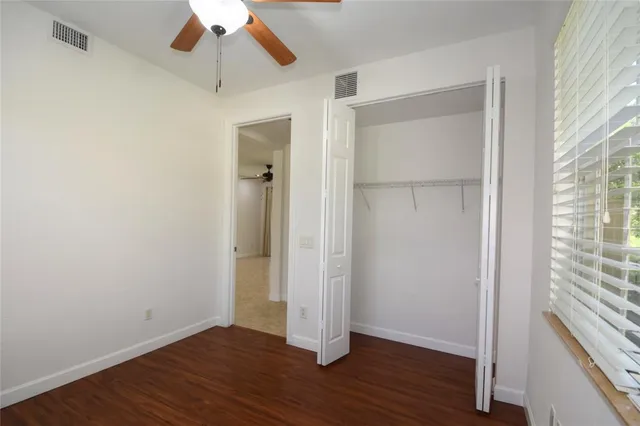 an empty room with wooden floor cabinet and windows