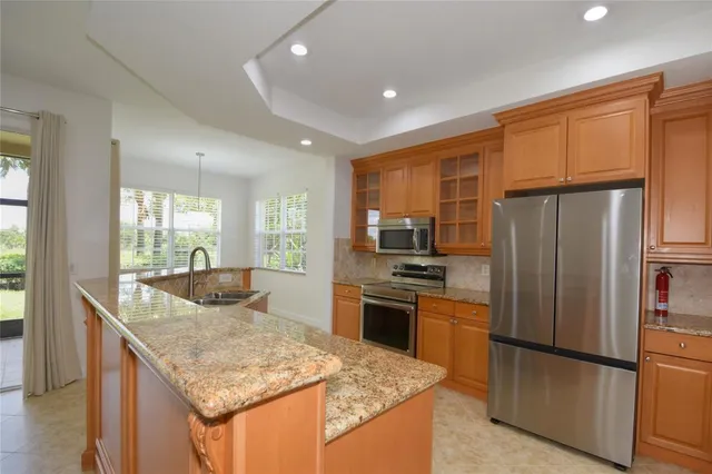 a kitchen with stainless steel appliances granite countertop a refrigerator a stove a sink a dining table and chairs