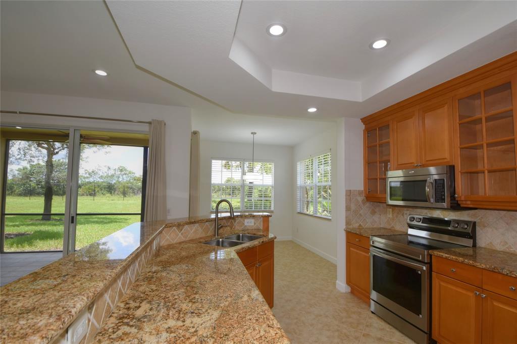8297 Northwest 128th Lane, Unit 20C Parkland, FL 33076 - Photo 10 of 42 a large kitchen with stainless steel appliances granite countertop a stove a sink and a granite counter top