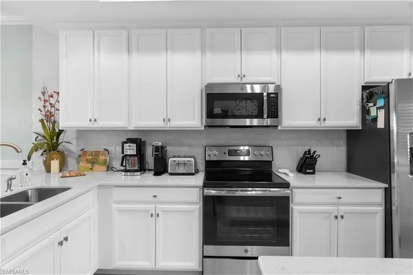 a kitchen with white cabinets and appliances