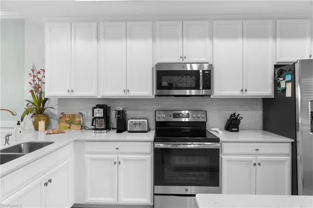 a kitchen with white cabinets and appliances
