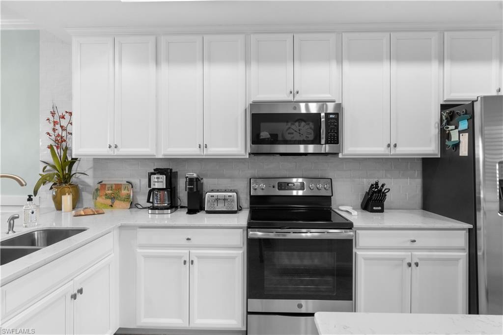 9578 Trevi Court, Unit 5135 Naples, FL 34113 - Photo 6 of 31 a kitchen with white cabinets and appliances