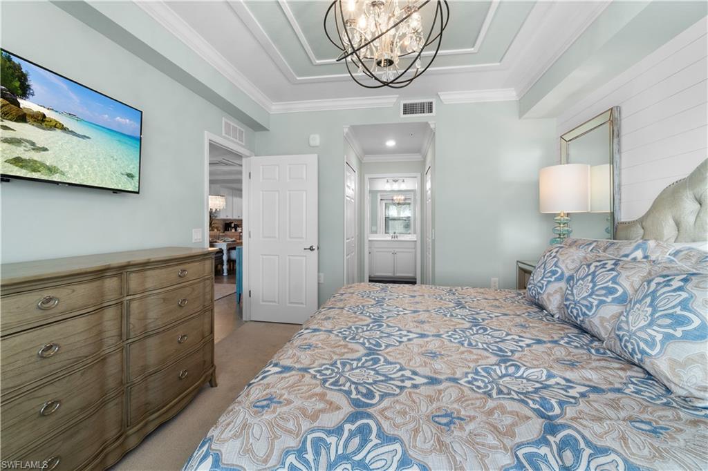9578 Trevi Court, Unit 5135 Naples, FL 34113 - Photo 10 of 31 a bedroom with a large bed and a chandelier