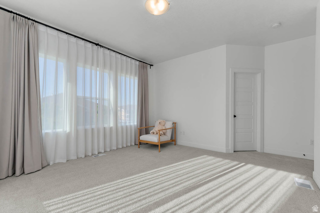 8307 Durham Street Sandy, UT 84070 - Photo 14 of 29 Spacious room featuring multiple large windows with sheer and blackout drapery, light-colored carpeting, a white panel door, and white baseboards