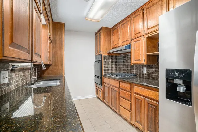 a kitchen with granite countertop a stove a sink and a microwave