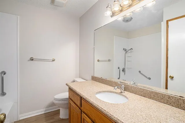 a bathroom with a granite countertop sink a mirror and a toilet