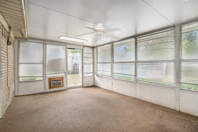 an empty room with chandelier a ceiling fan and windows