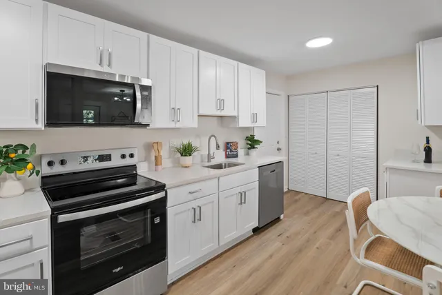 a kitchen with stainless steel appliances a stove a sink cabinets and a wooden floor