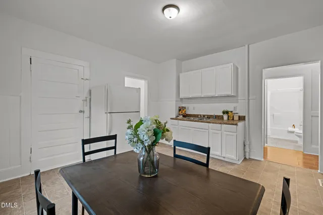a kitchen with white cabinets and dining table