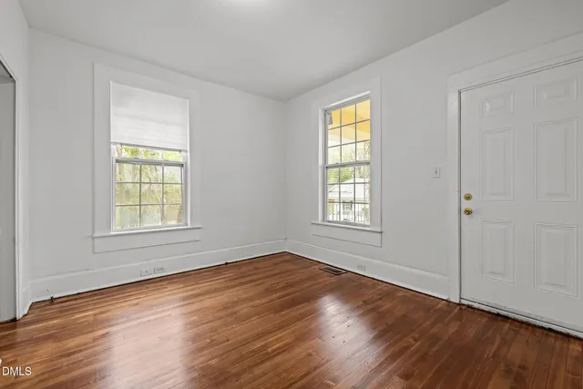 a view of an empty room with wooden floor and a window