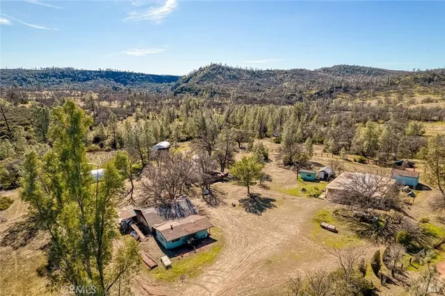 an aerial view of residential house with yard and mountain view in back