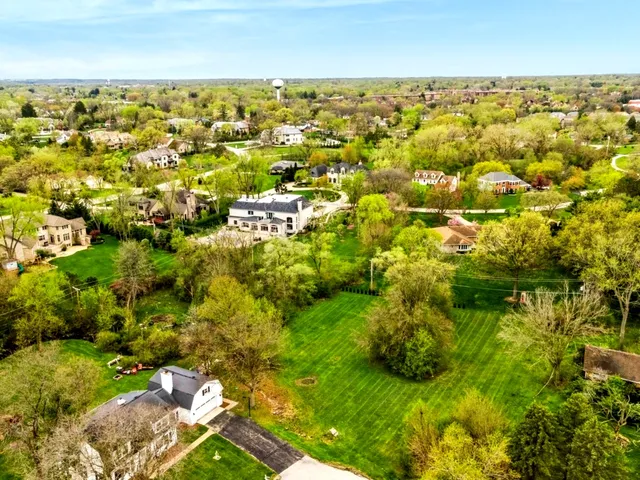 an aerial view of residential houses with outdoor space and trees