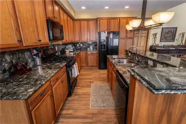 a kitchen with stainless steel appliances granite countertop a stove a sink dishwasher and a refrigerator