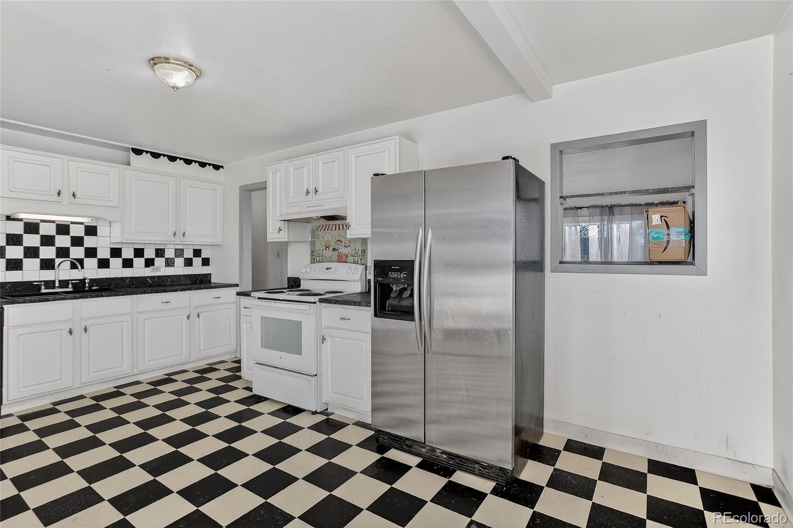 1279 South Raritan Street Denver, CO 80223 - Photo 8 of 21 a kitchen with a checkered floor and white cabinets