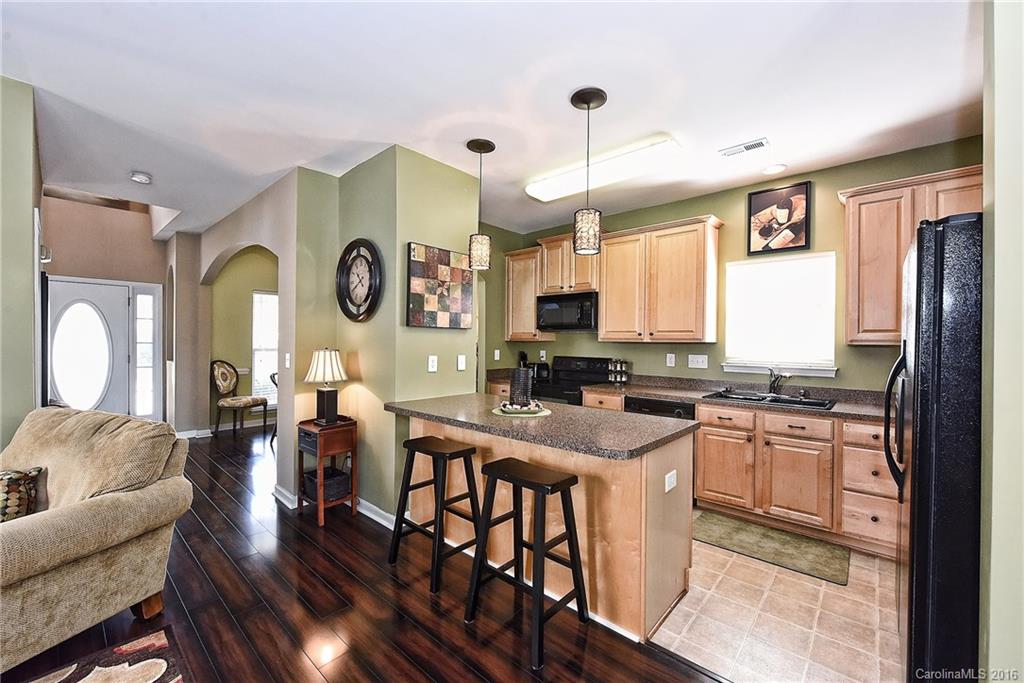 8905 Washam Potts Road Cornelius, NC 28031 - Photo 13 of 24 a kitchen with stainless steel appliances granite countertop a stove a refrigerator a dining table and chairs with wooden floor