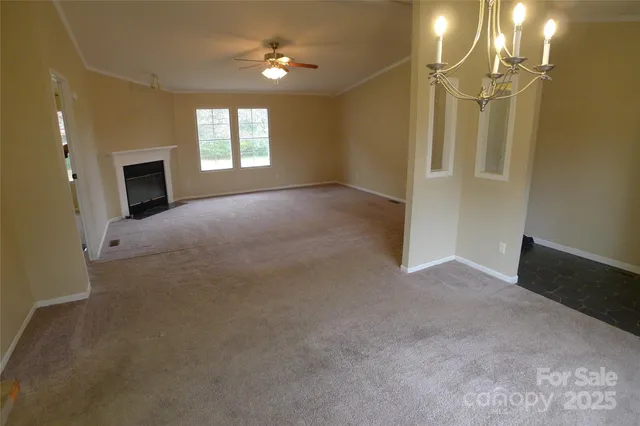 an empty room with windows and chandelier fan