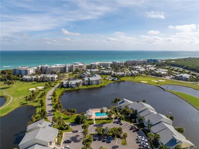 an aerial view of ocean and residential houses with outdoor space