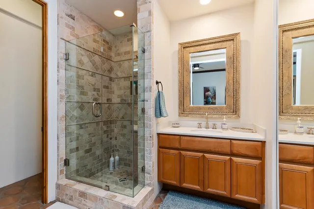 a bathroom with a granite countertop sink a mirror and shower