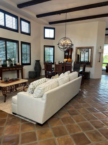 a living room with couches a fireplace and a dining table with wooden floor