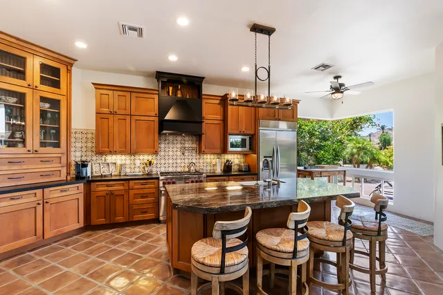 a kitchen with stainless steel appliances granite countertop a stove a sink dishwasher a dining table and chairs with wooden floor