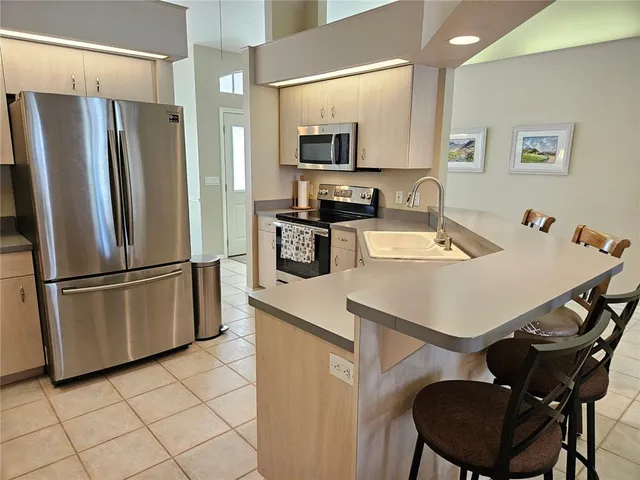 a kitchen with stainless steel appliances a refrigerator a stove a sink a dining table and chairs