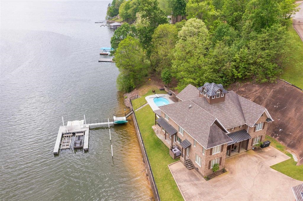 Waterfront property featuring a private boat dock with two boat lifts, an in-ground swimming pool, and mature trees