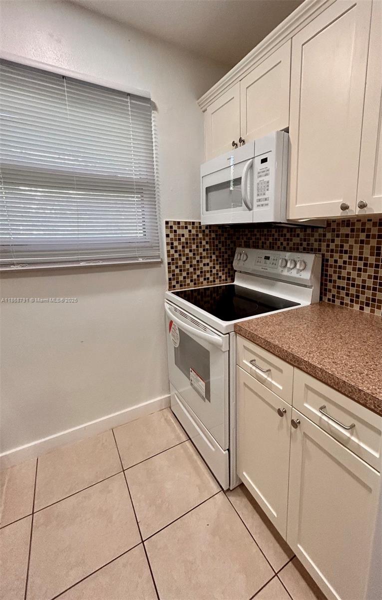 3265 Griffin Road, Unit 205 Dania Beach, FL 33312 - Photo 7 of 13 a white kitchen with granite countertop white cabinets and white appliances