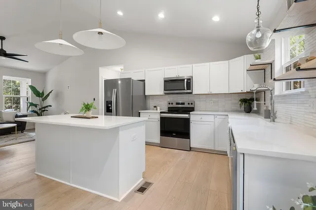 a kitchen with kitchen island a sink stainless steel appliances and cabinets