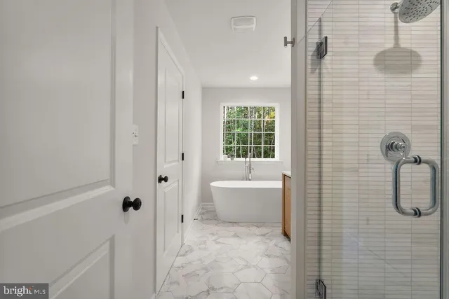 a bathroom with a tub a window and a shower