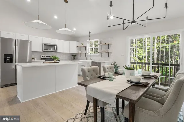 a view of a dining room and livingroom with furniture wooden floor a chandelier