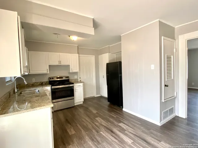 a kitchen with granite countertop a refrigerator and a stove top oven