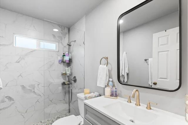 a bathroom with a sink vanity mirror and toilet