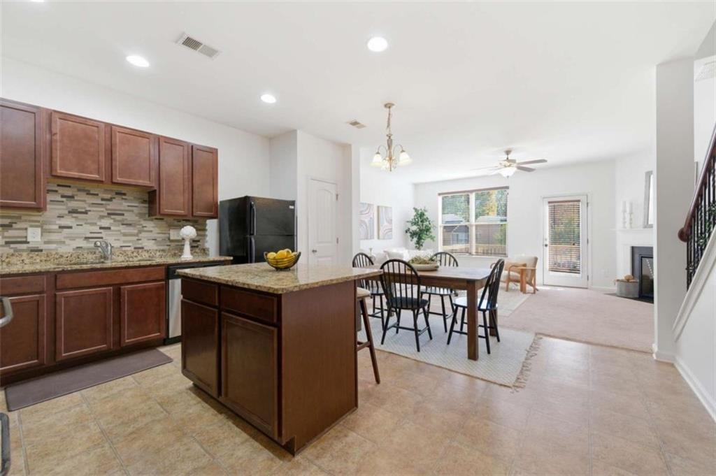 6872 Zaniah Road South Fulton, GA 30331 - Photo 4 of 29 a kitchen with stainless steel appliances granite countertop a stove top oven a sink dishwasher a dining table and chairs with wooden floor
