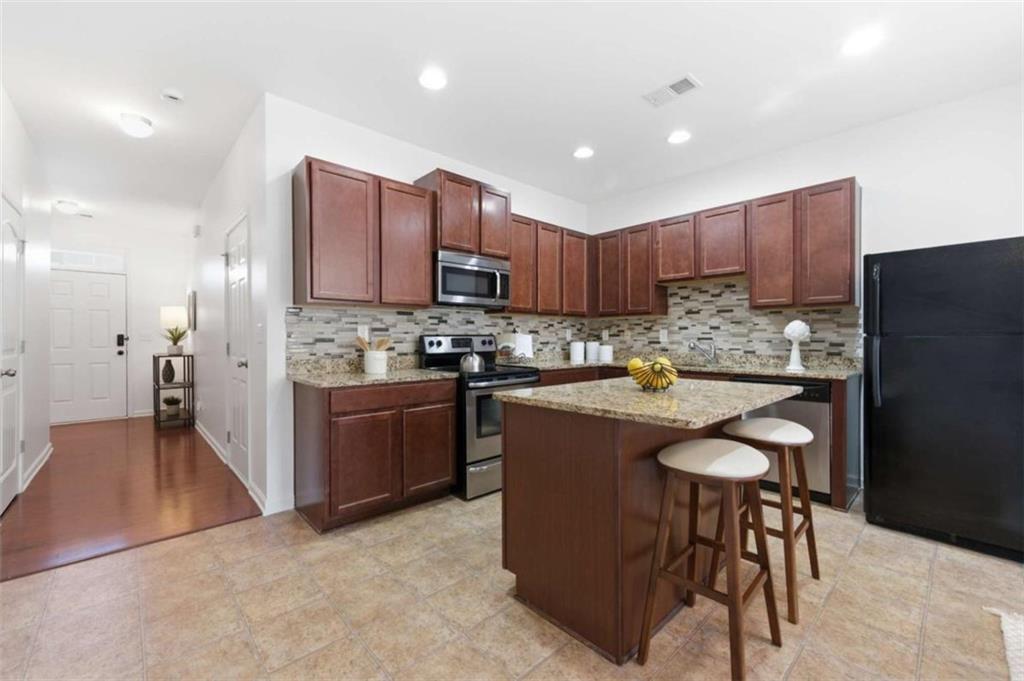 6872 Zaniah Road South Fulton, GA 30331 - Photo 5 of 29 a kitchen with kitchen island granite countertop wooden cabinets and a stainless steel appliances