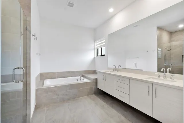 a spacious bathroom with a double vanity sink a mirror and a bathtub