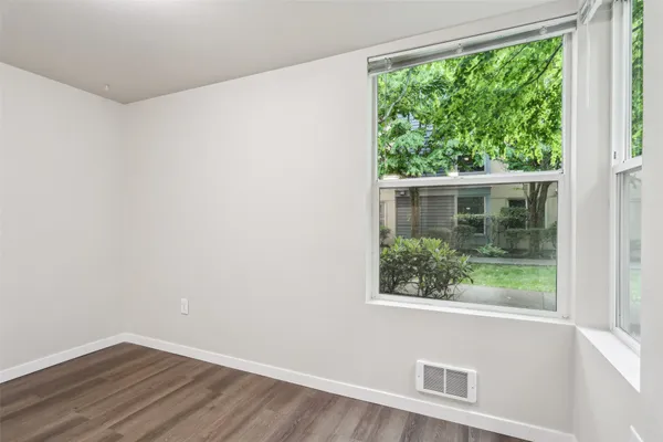 a view of an empty room with wooden floor and a window
