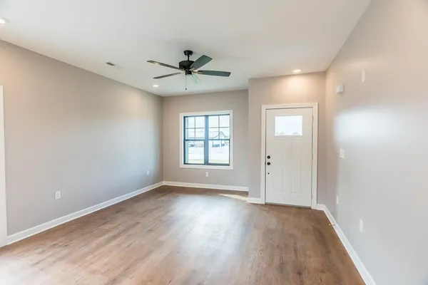 a view of an empty room with a window and wooden floor