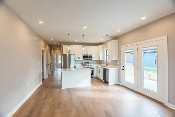 a living room with stainless steel appliances furniture and a kitchen view