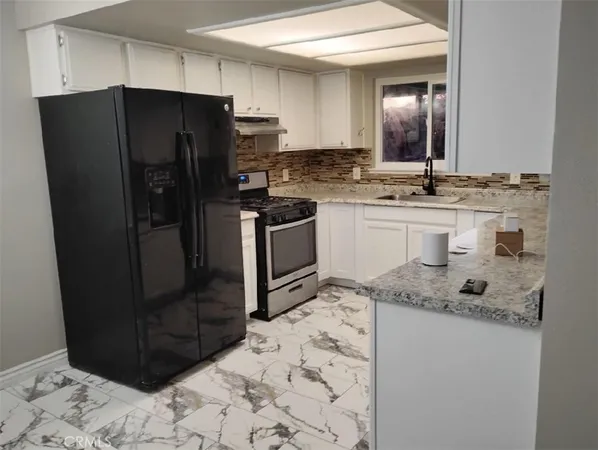 a kitchen with stainless steel appliances granite countertop a refrigerator and a stove
