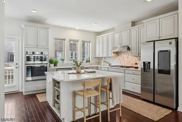 a kitchen with stainless steel appliances granite countertop a white cabinets and a refrigerator