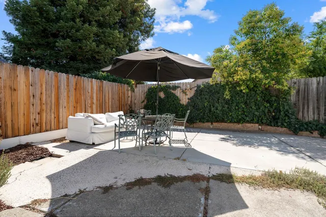 a view of a patio with table and chairs potted plants and a palm tree