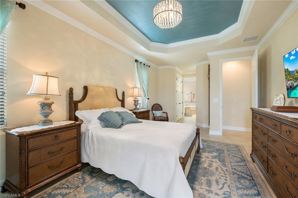 28529 Westmeath Court Bonita Springs, FL 34135 - Photo 12 of 49 a bedroom with a large bed and a chandelier