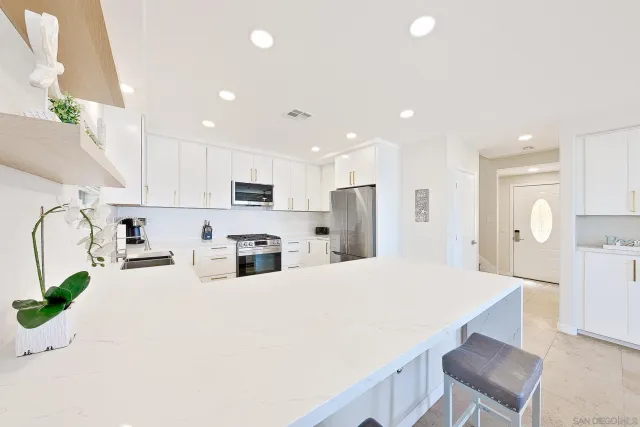 a kitchen with kitchen island white cabinets and refrigerator
