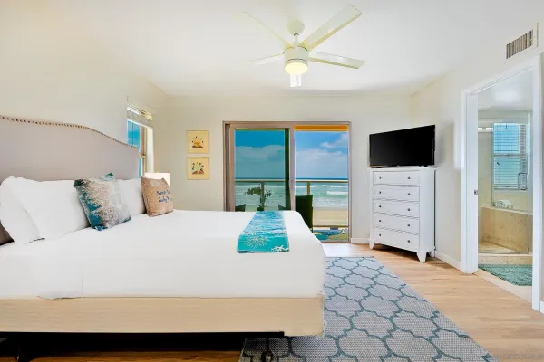 a bedroom with a large bed and a flat tv screen on dresser