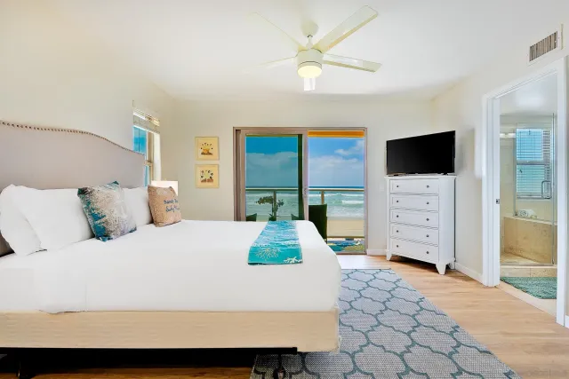 a bedroom with a large bed and a flat tv screen on dresser