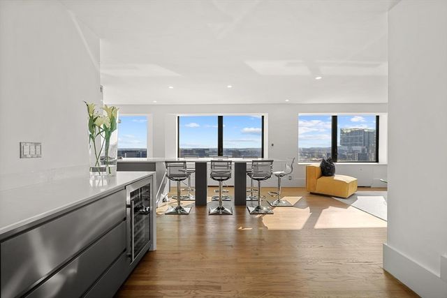 a living room with couches and kitchen view with wooden floor