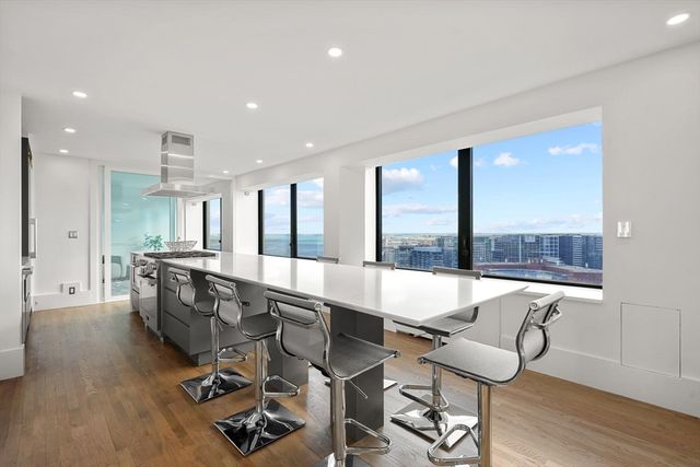 a large dining hall with stainless steel appliances granite countertop a barbecue grill and couches with wooden floor