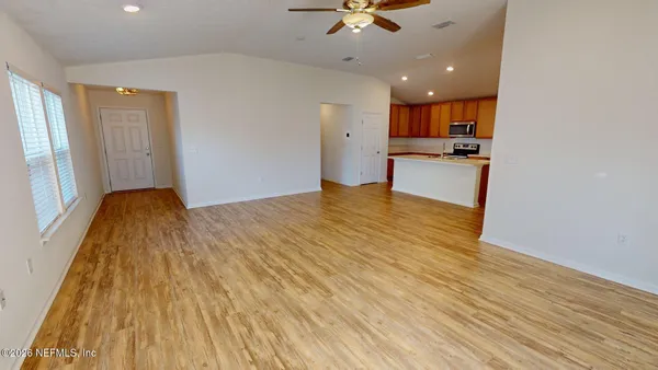 a large white kitchen with wooden floors and stainless steel appliances